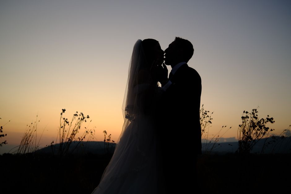 A newlywed couple embracing in a scenic landscape at sunset
